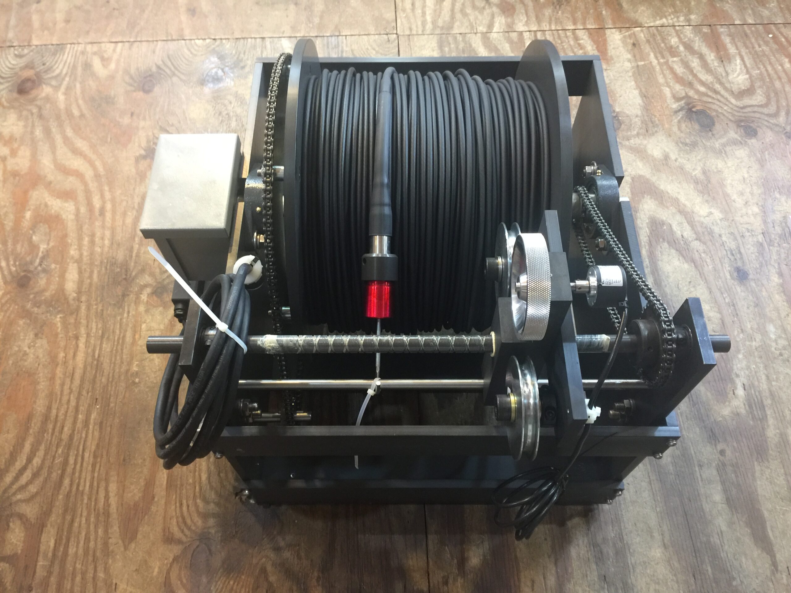 Black Cable Reel on a Metal Frame With a Red Button on Top